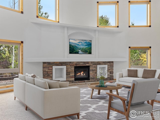 carpeted living room featuring a towering ceiling, plenty of natural light, and a stone fireplace