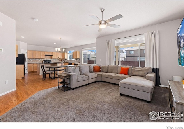 living room with hardwood / wood-style floors and ceiling fan with notable chandelier