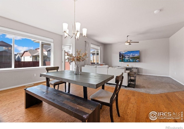 dining area featuring light hardwood / wood-style flooring and ceiling fan with notable chandelier