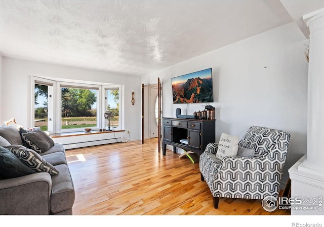 living area with a baseboard heating unit and light wood finished floors