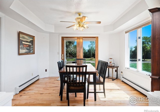 dining room featuring a tray ceiling, light wood-style floors, and baseboard heating