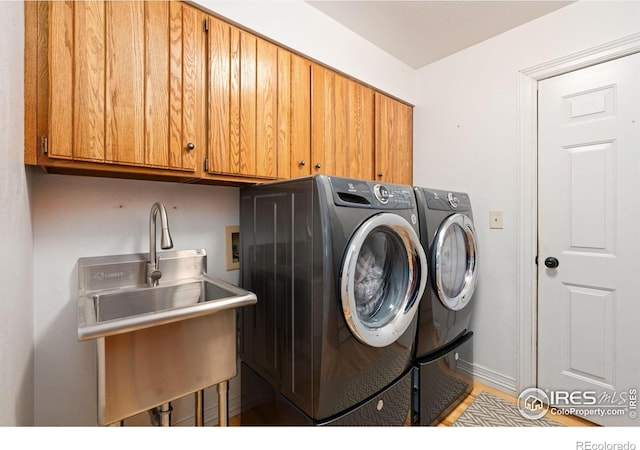 laundry room with baseboards, cabinet space, a sink, and independent washer and dryer