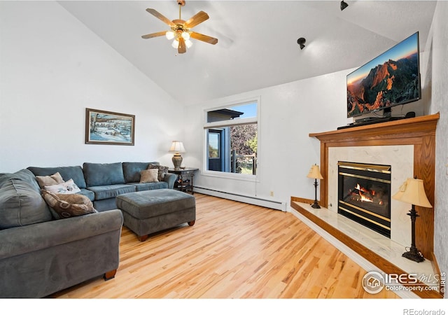 living area with ceiling fan, wood finished floors, a fireplace, and a baseboard radiator