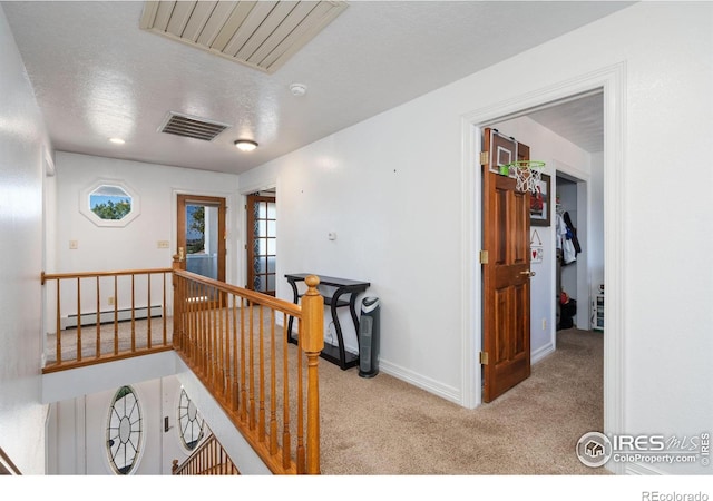 hallway featuring baseboard heating, visible vents, carpet, and an upstairs landing