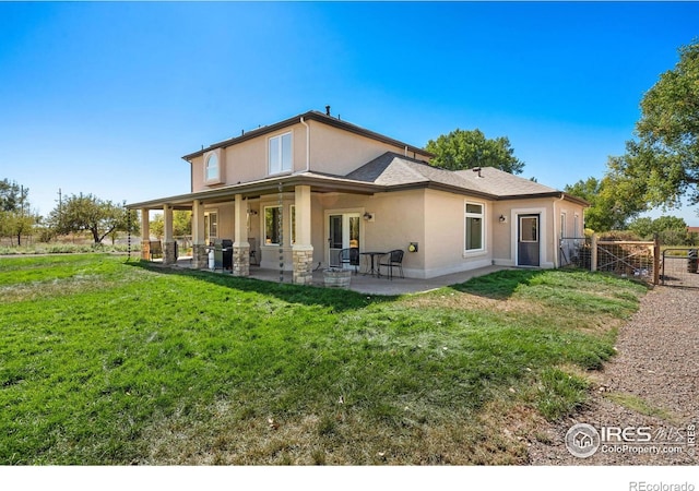 rear view of property featuring a gate, fence, a patio area, a lawn, and stucco siding
