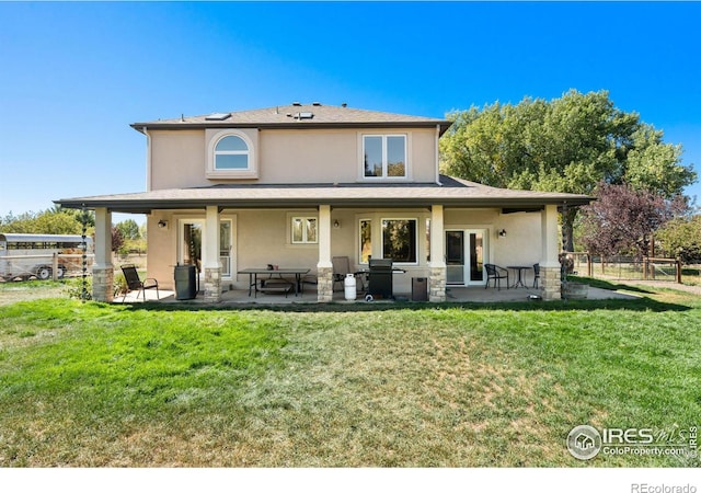 rear view of house featuring a yard, a patio area, stucco siding, and fence