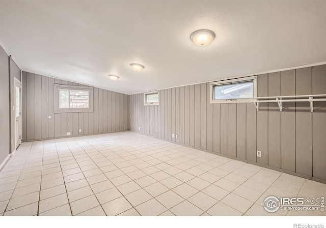 basement with light tile patterned floors and wooden walls