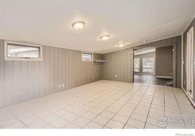 tiled spare room with lofted ceiling and wood walls