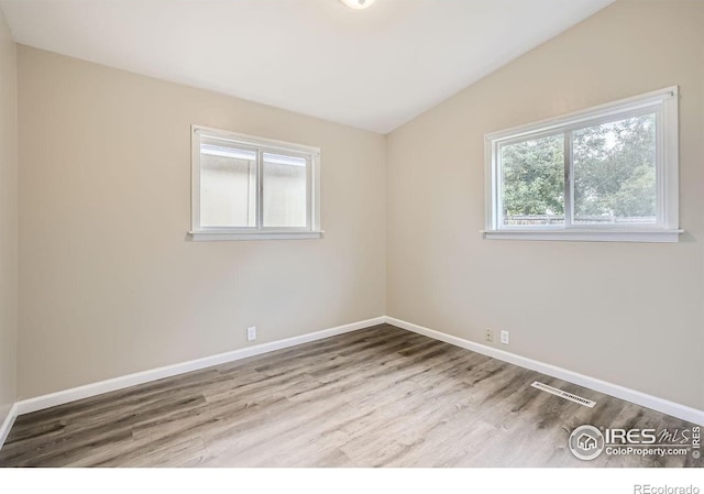 empty room featuring vaulted ceiling and light hardwood / wood-style flooring