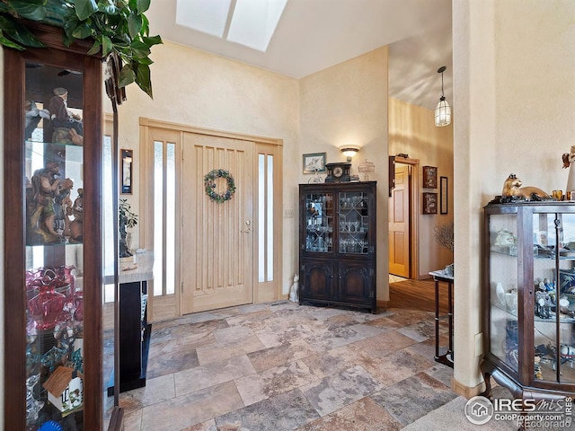 foyer featuring a towering ceiling and a skylight