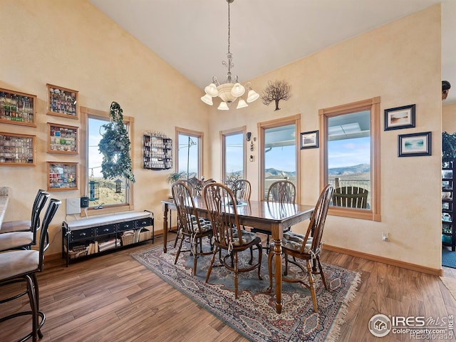 dining room with hardwood / wood-style flooring, high vaulted ceiling, and an inviting chandelier