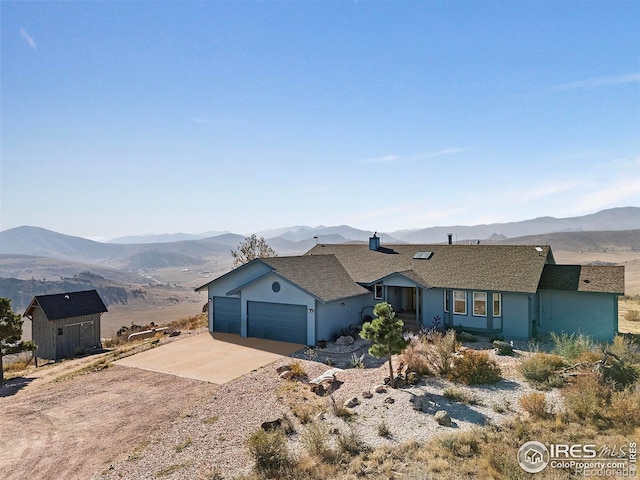 single story home with a storage shed, a mountain view, and a garage