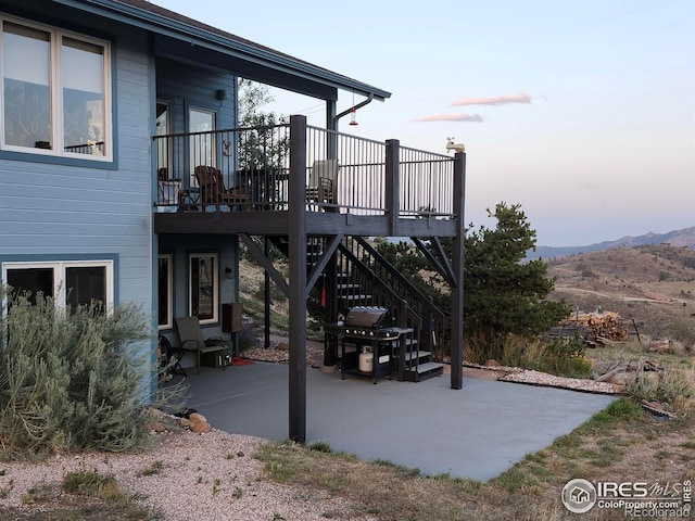 patio terrace at dusk with a grill and a deck with mountain view