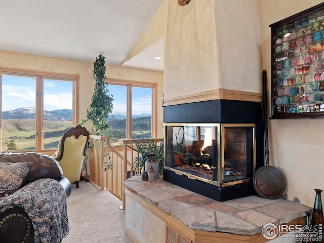 carpeted living room with a mountain view, a multi sided fireplace, and vaulted ceiling