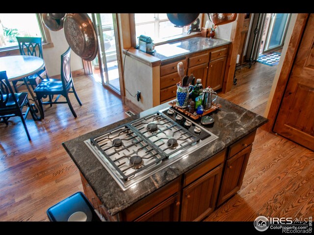 kitchen featuring light wood-type flooring, dark stone countertops, and stainless steel gas cooktop