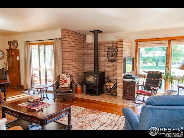 living room with light hardwood / wood-style flooring, a wood stove, and plenty of natural light