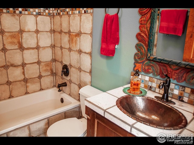 full bathroom featuring tiled shower / bath combo, vanity, and toilet