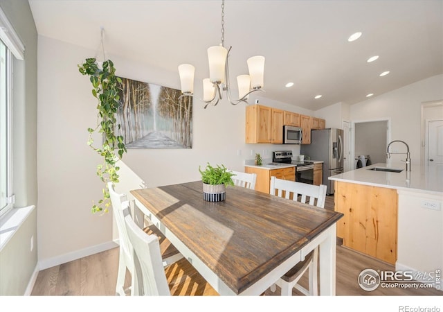 dining room featuring vaulted ceiling, light hardwood / wood-style flooring, a chandelier, and sink