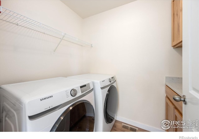 laundry room featuring wood-type flooring, cabinets, and washing machine and clothes dryer