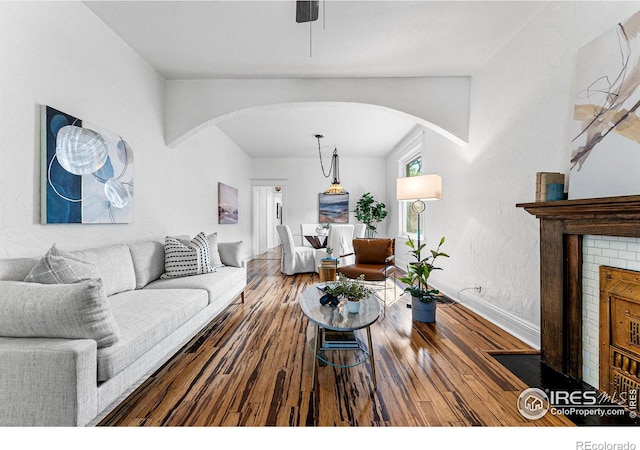 living room featuring wood-type flooring and a brick fireplace