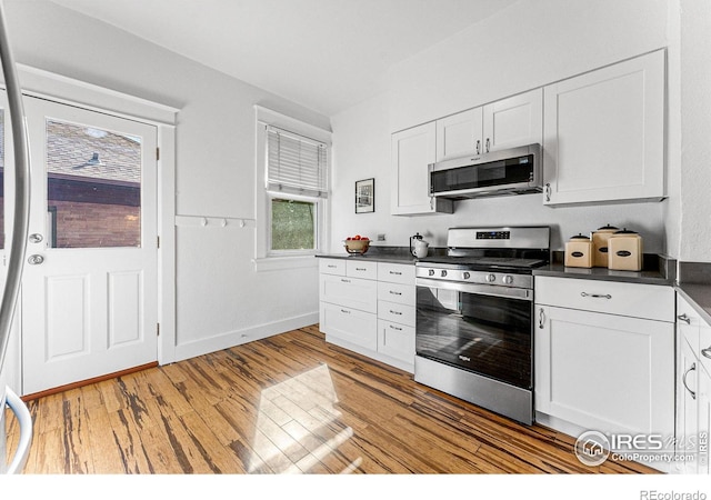 kitchen with light hardwood / wood-style flooring, appliances with stainless steel finishes, and white cabinetry