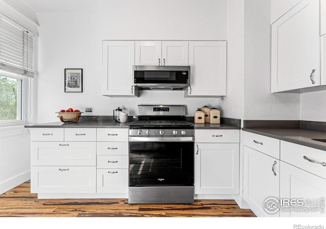 kitchen with stainless steel appliances, light hardwood / wood-style floors, and white cabinetry