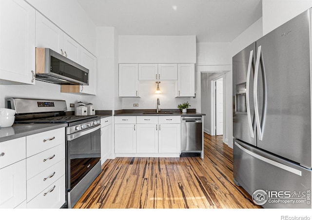 kitchen with white cabinets, sink, appliances with stainless steel finishes, and light hardwood / wood-style floors