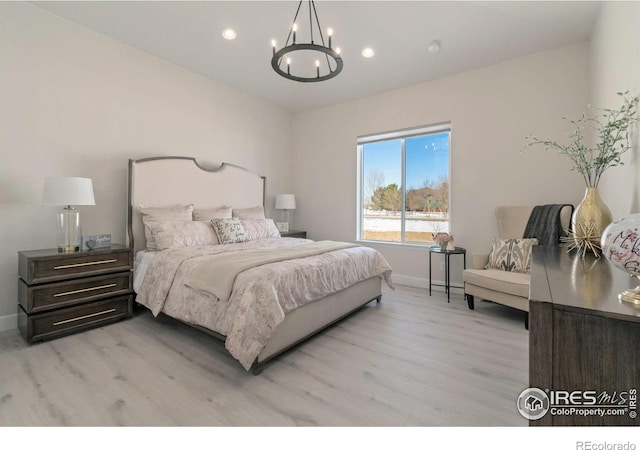 bedroom featuring light wood-type flooring and an inviting chandelier