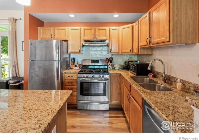 kitchen featuring light wood-type flooring, sink, backsplash, appliances with stainless steel finishes, and light stone countertops