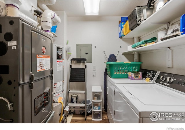 laundry area with heating unit, independent washer and dryer, electric panel, and hardwood / wood-style floors