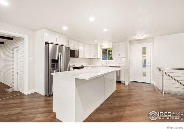 kitchen with stainless steel appliances, dark wood-type flooring, white cabinetry, and a center island