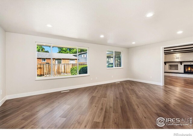 unfurnished living room with dark hardwood / wood-style floors and a brick fireplace