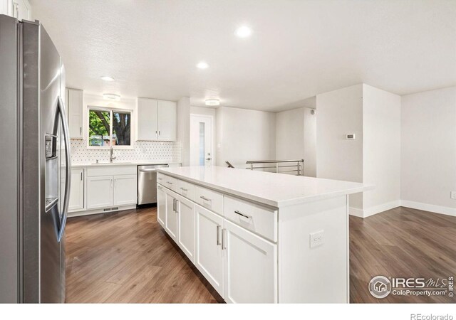 kitchen with sink, white cabinets, a kitchen island, stainless steel appliances, and dark hardwood / wood-style flooring