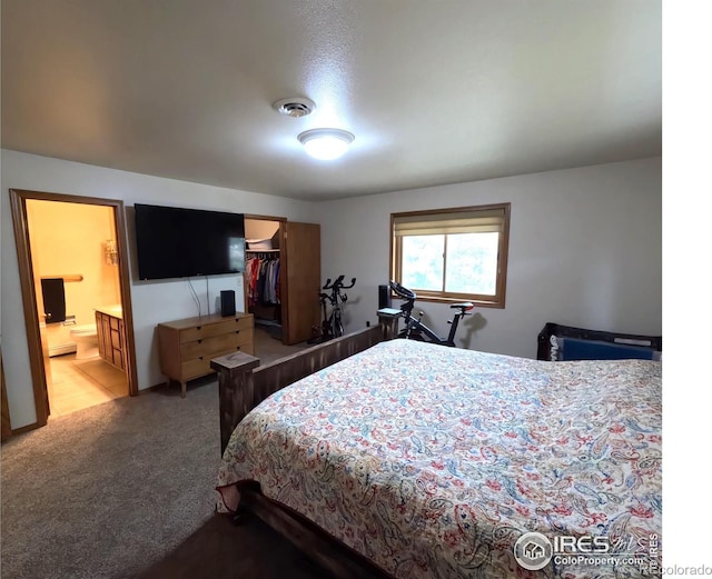 carpeted bedroom with ensuite bathroom, a closet, and visible vents