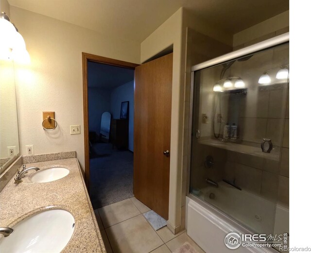 full bathroom featuring double vanity, combined bath / shower with glass door, a sink, and tile patterned floors