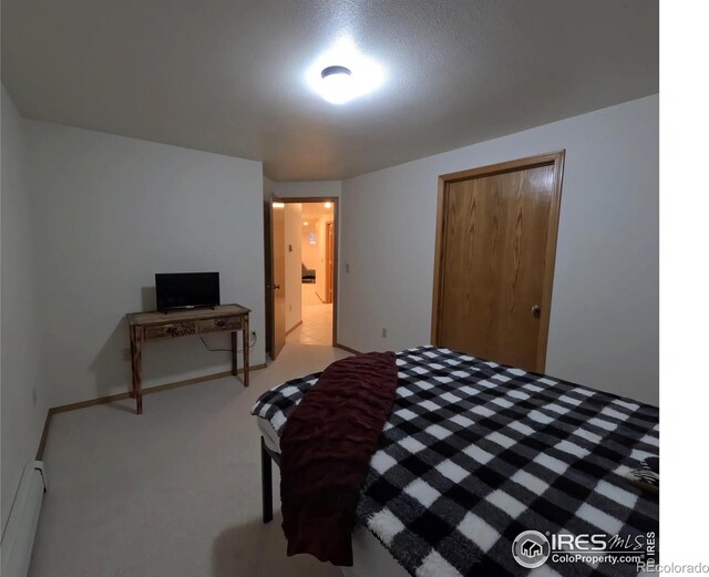 bedroom with a closet, a baseboard heating unit, and carpet flooring