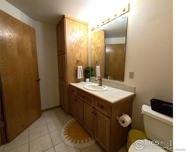 bathroom featuring tile patterned flooring, vanity, and toilet