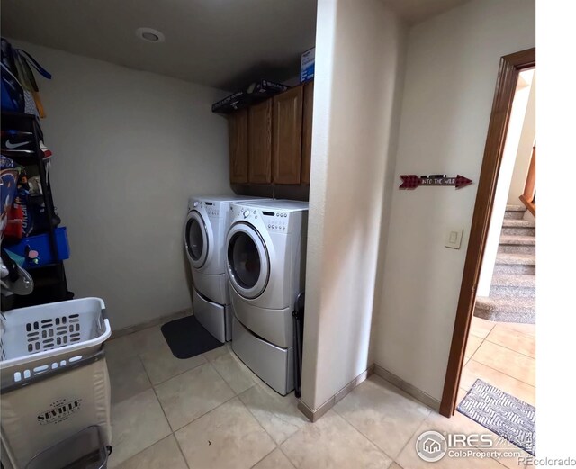 laundry room featuring cabinet space, baseboards, washer and dryer, and light tile patterned flooring