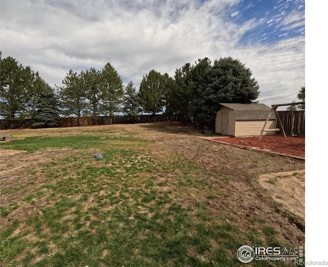 view of yard featuring a storage shed, fence, and an outbuilding