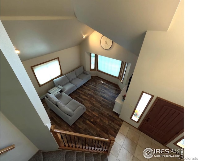 tiled living area featuring vaulted ceiling and stairs