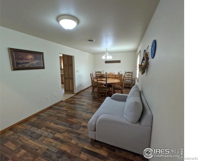 living room with dark wood-style floors, baseboards, visible vents, and a chandelier