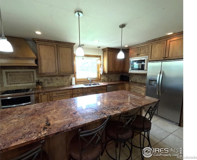 kitchen with custom exhaust hood, stainless steel appliances, a sink, and a kitchen breakfast bar