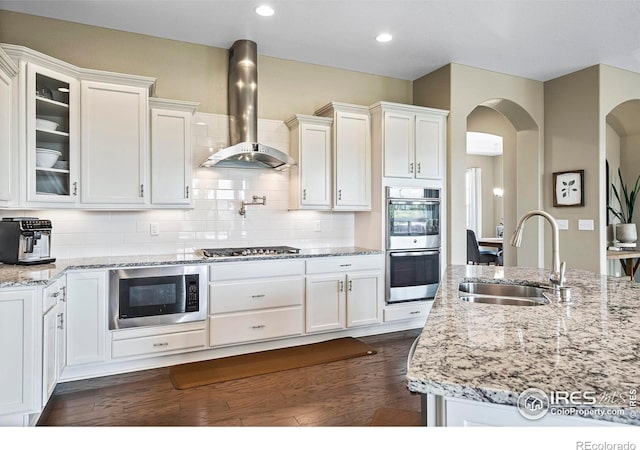 kitchen featuring white cabinets, appliances with stainless steel finishes, sink, and wall chimney range hood