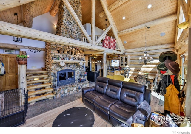 living room featuring high vaulted ceiling, a stone fireplace, beamed ceiling, an inviting chandelier, and light hardwood / wood-style flooring