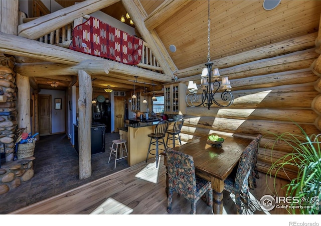 unfurnished dining area featuring dark hardwood / wood-style flooring, a chandelier, rustic walls, and high vaulted ceiling