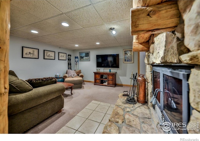 carpeted living room featuring a paneled ceiling and a stone fireplace