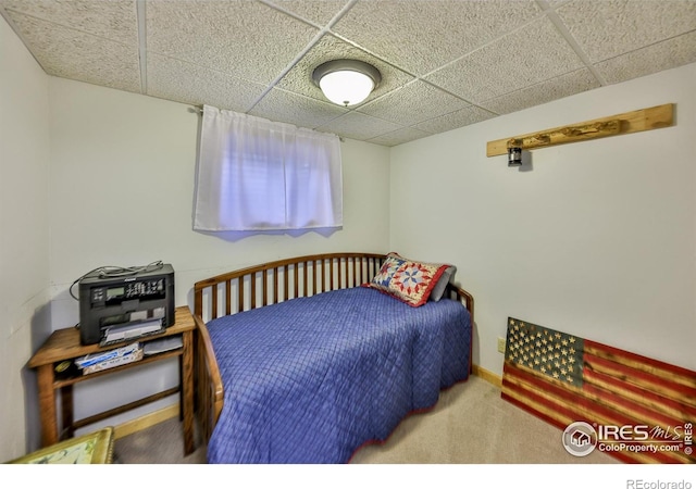 carpeted bedroom featuring a drop ceiling