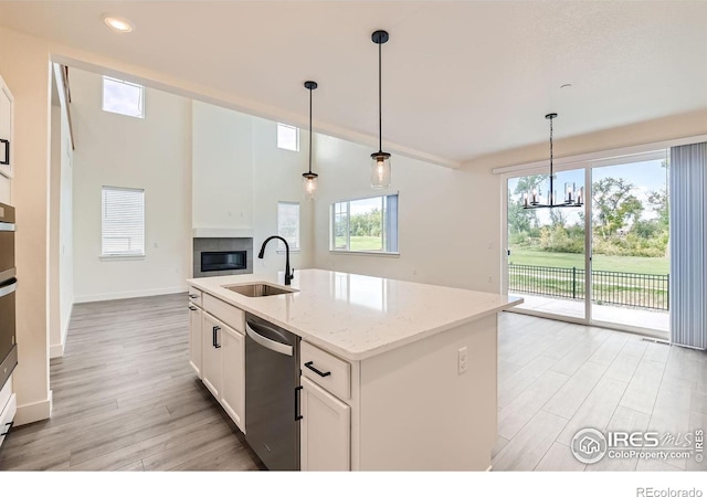 kitchen featuring dishwasher, white cabinetry, a kitchen island with sink, and a wealth of natural light