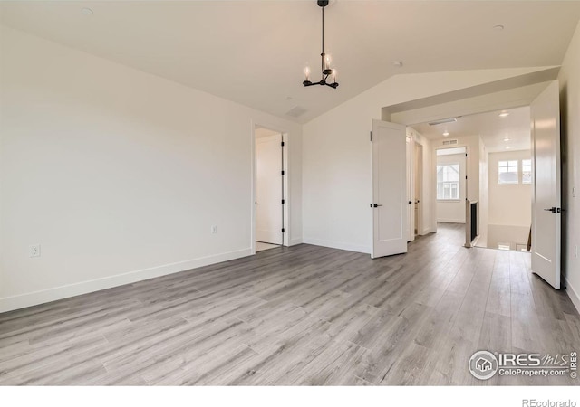 unfurnished room featuring light hardwood / wood-style flooring, lofted ceiling, and an inviting chandelier