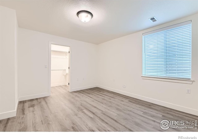 empty room featuring a textured ceiling and light hardwood / wood-style floors